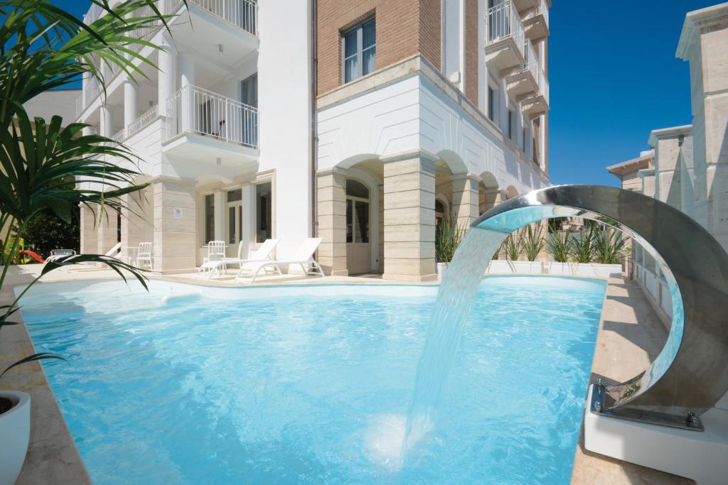 a pool with a water fountain in front of a building at Residence Hotel Alba Palace in Alba Adriatica