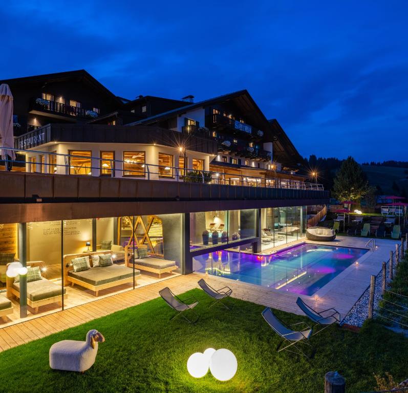 une grande maison avec une piscine la nuit dans l'établissement Saltria - your Alpine experience, à Alpe di Siusi