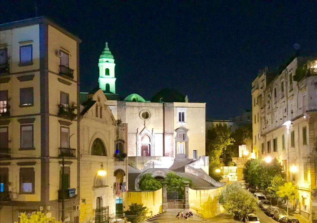 un edificio con una chiesa con una torre dell'orologio di notte di Casa Scialò Cuore di Napoli a Napoli