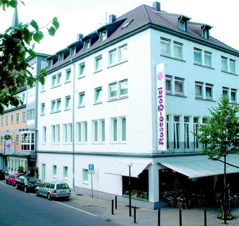 ein weißes Gebäude mit einem Schild an der Seite in der Unterkunft Rosenhotel in Zweibrücken