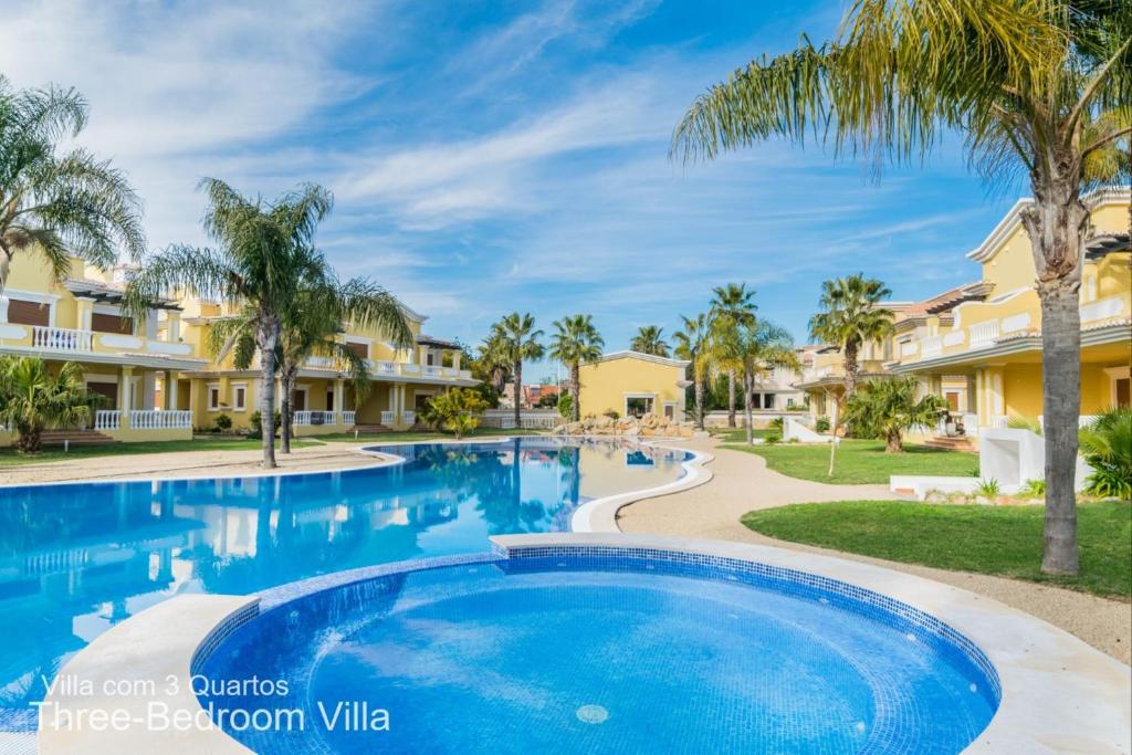 a swimming pool at a resort with palm trees and condos at Akivillas Tavira Conceicao in Conceição