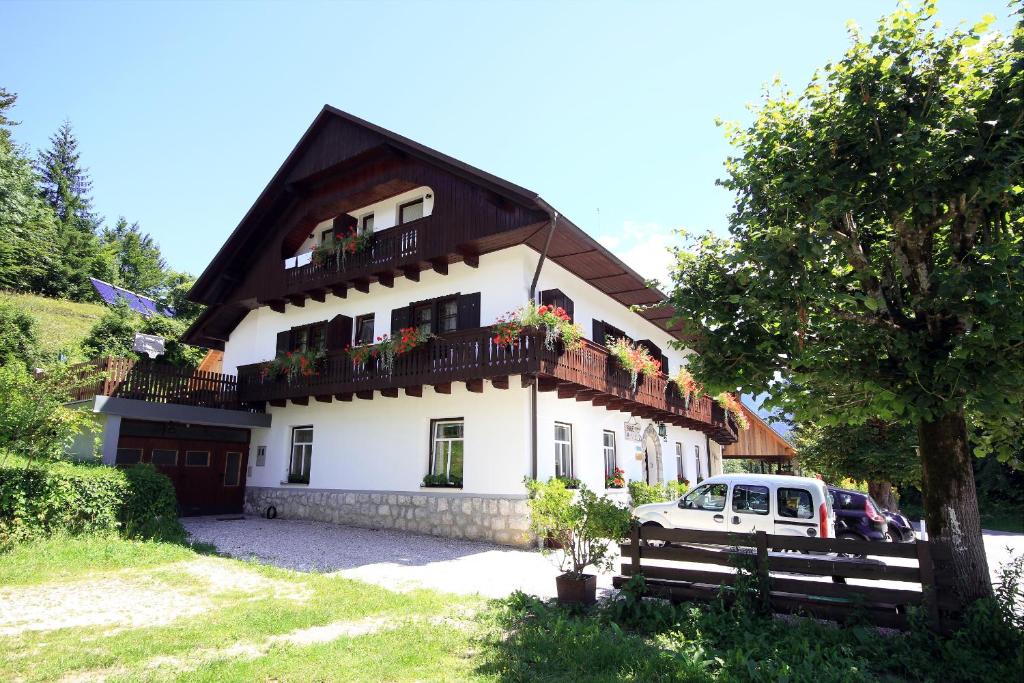 una casa blanca con balcones y un coche aparcado delante en Accommodation Resman, en Bohinj