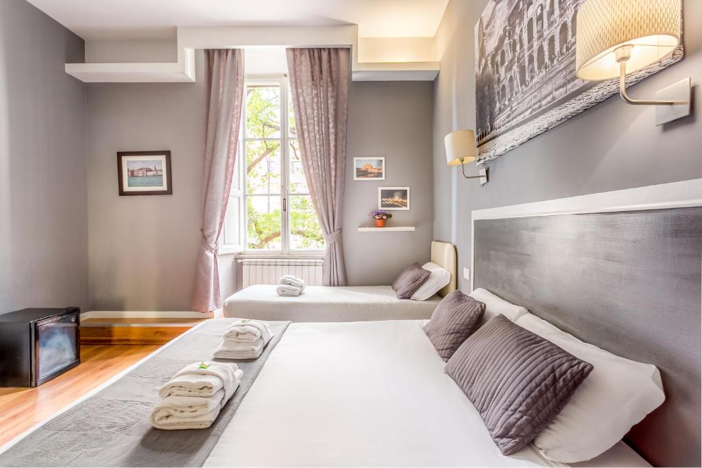 um quarto com 2 camas e uma grande janela em AmoRoma Suite em Roma