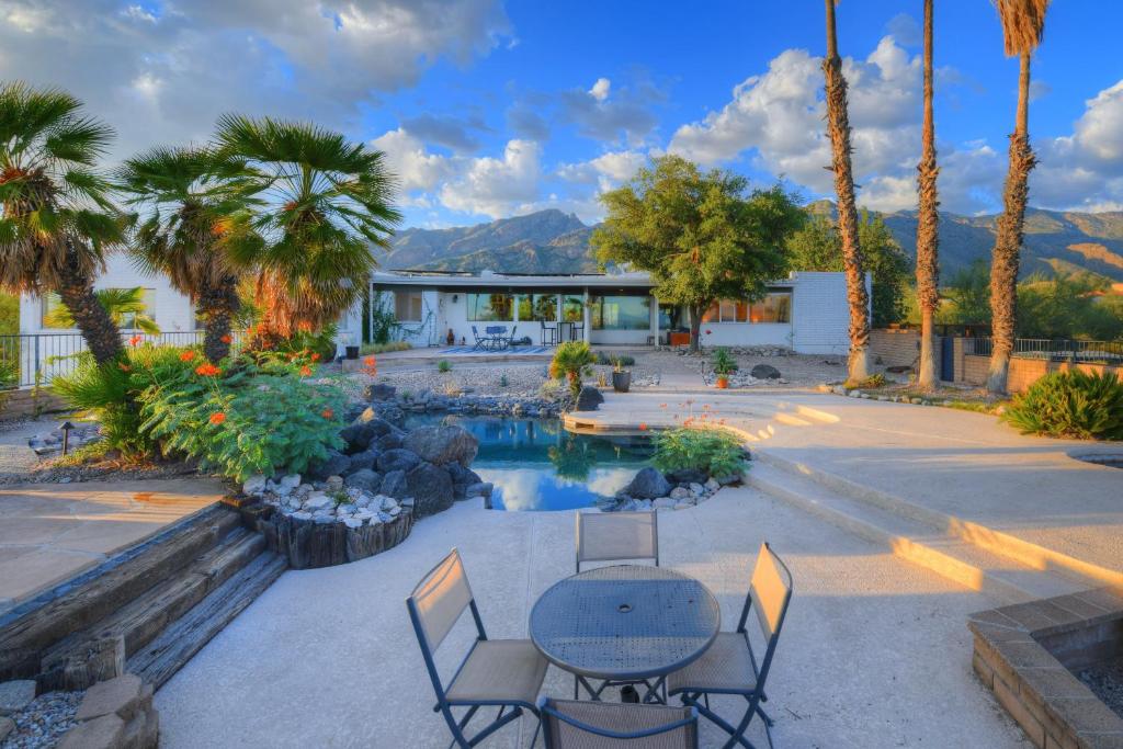 un patio con mesa, sillas y palmeras en Skyline Bel Air Estates en Tucson