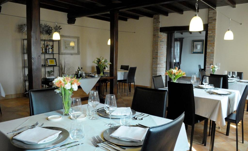 un comedor con mesas blancas y sillas con flores. en La Locanda, en Calvignano