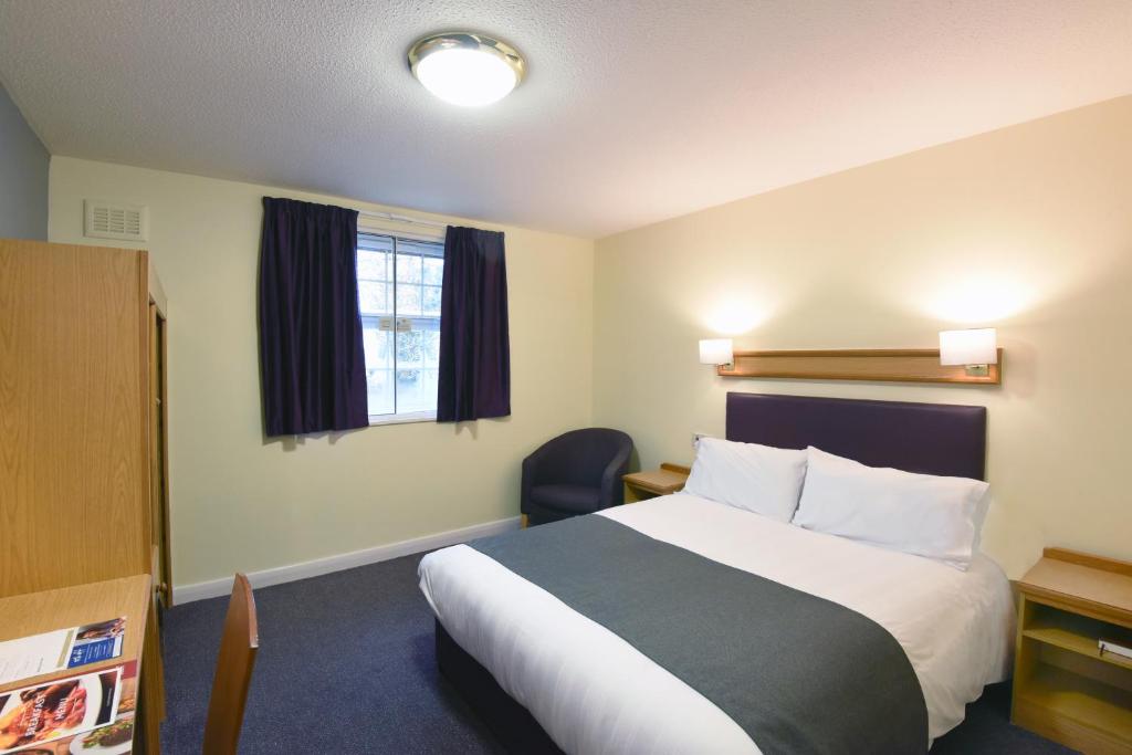 een hotelkamer met een bed en een stoel bij The Mount by Greene King Inns in Wigan