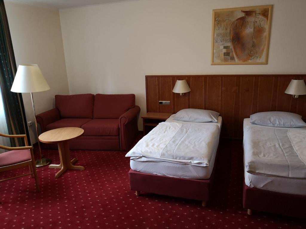 a hotel room with two beds and a couch at Hotel & Ristorante Il Duomo in Olpe