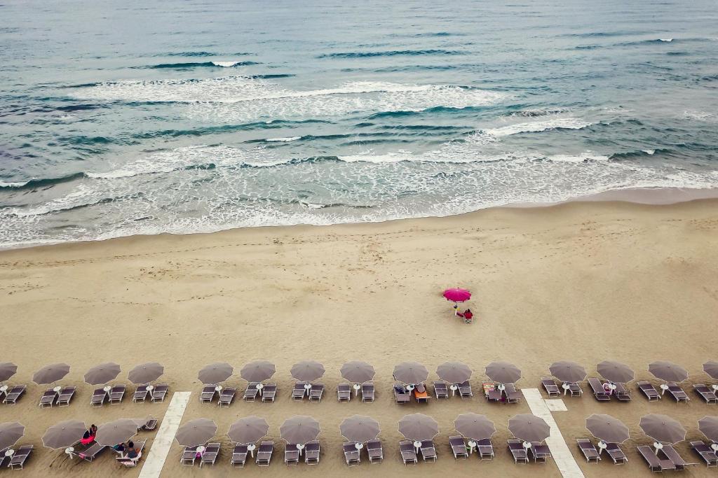 eine Aussicht über einen Strand mit Stühlen und einem Sonnenschirm in der Unterkunft Ancora Resort in Acciaroli