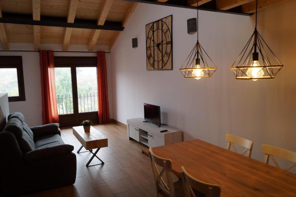ein Wohnzimmer mit einem Tisch, einem Sofa und einem TV in der Unterkunft Puente viejo de Buitrago casa Enebro in Buitrago del Lozoya