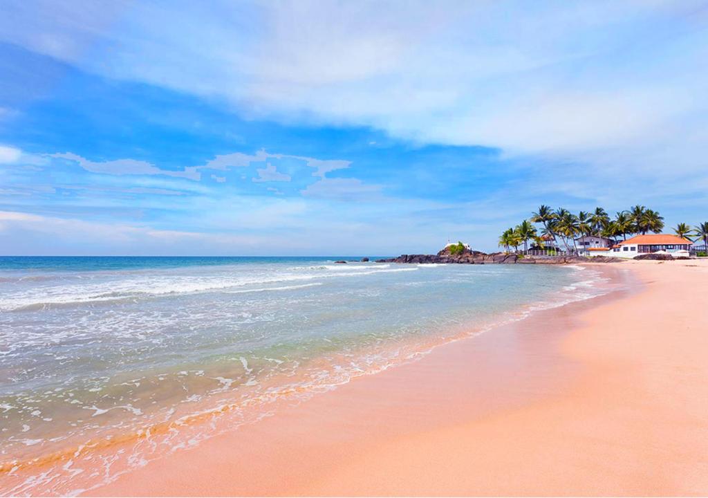 uma praia arenosa com palmeiras e o oceano em Villa184 em Ahungalla