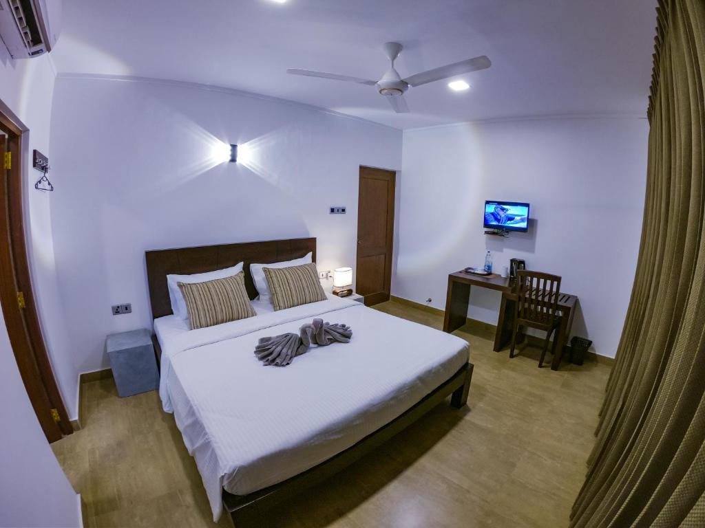 um quarto com uma cama e uma secretária com uma televisão em Bony's Holiday Inn Negombo em Negombo