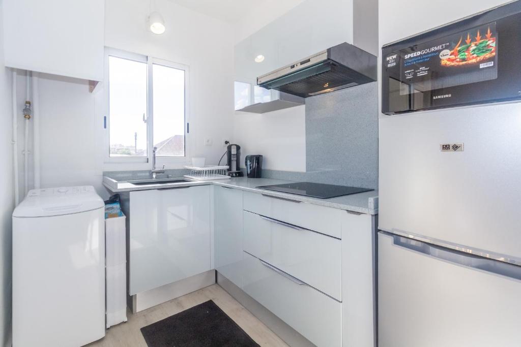 a white kitchen with a sink and a refrigerator at Montreuil - joli T2 refait à neuf centre-ville de Saint-Denis in Saint-Denis