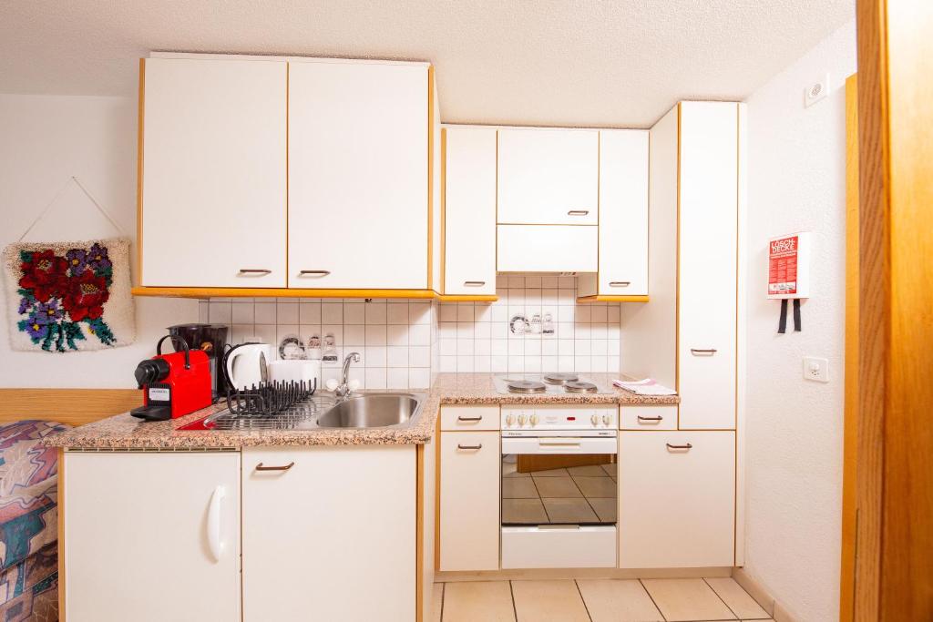 a kitchen with white cabinets and a sink at Haus Alfa in Saas-Fee