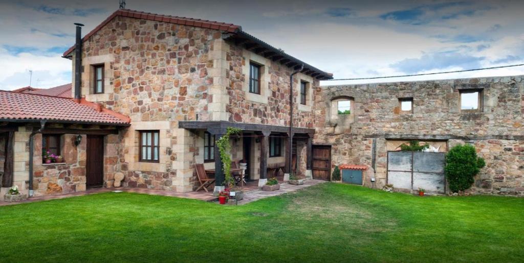 una gran casa de piedra con un patio verde en Casa Rural La Panera, en Cillamayor
