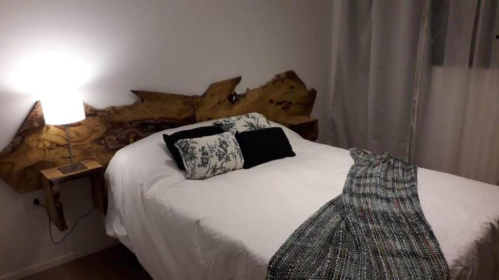 Un dormitorio con una cama blanca con cabecero de madera. en Bariloche Apart, en San Carlos de Bariloche