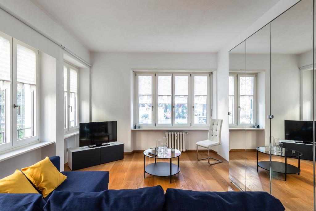 a living room with a blue couch and tables and windows at Tigli Apartment by Quokka 360 - bright lakeside flat in Lugano