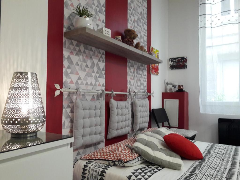 - une chambre avec des murs rouges et blancs et un lit avec des oreillers dans l'établissement Appartement T1 Hyper Centre place de la Victoire, à Bordeaux