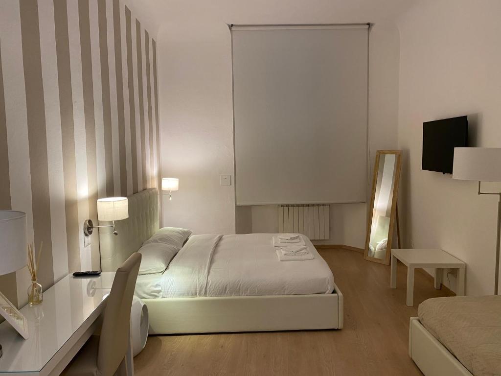 1 dormitorio con cama, mesa y TV en B&B Sallustio Rooms, en Siena