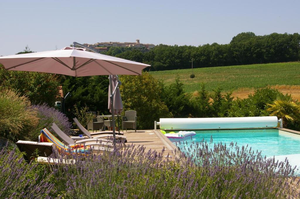 een parasol en stoelen naast een zwembad bij Castel Mazars in Castelnau-de-Montmiral