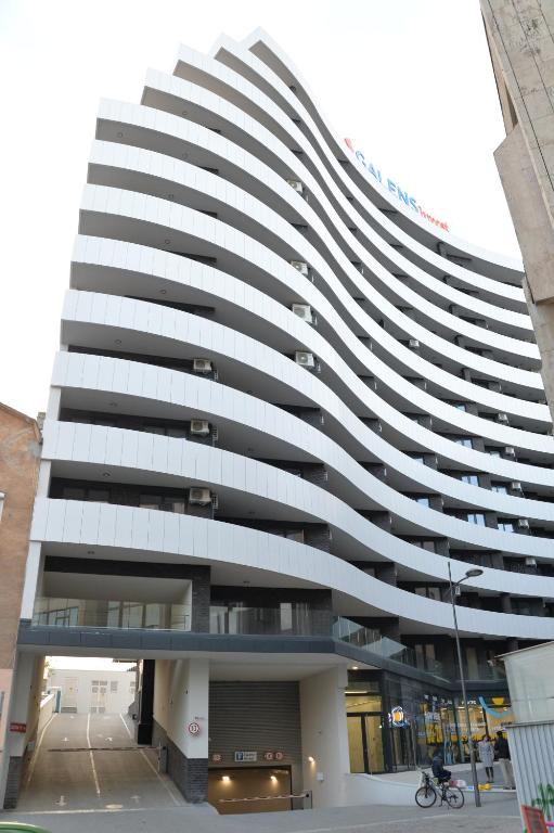 ein hohes weißes Gebäude mit vielen Fenstern in der Unterkunft Pupin Palata business apartman B5 in Novi Sad