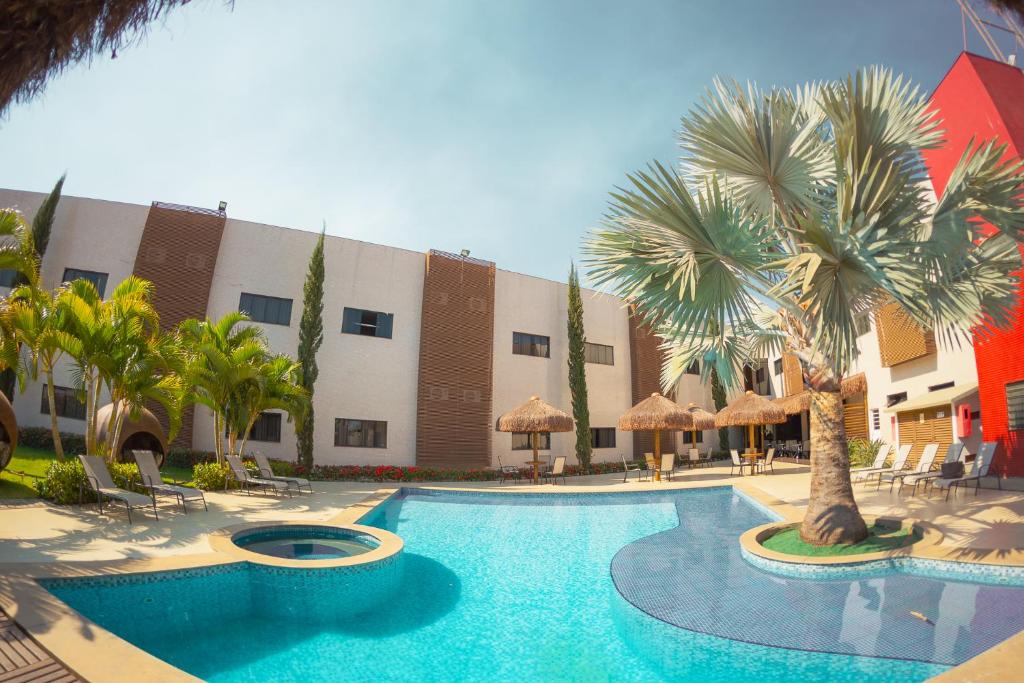 a swimming pool with palm trees in front of a building at Sofisticatto Park Hotel in Formosa