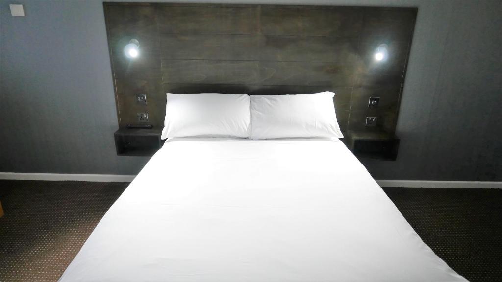 a bed with two white pillows in a room at Warrens Village Motel and Self Catering in Clevedon