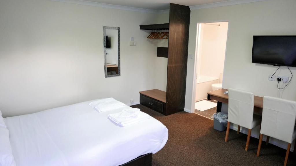a room with a bed and a desk and a television at Warrens Village Motel and Self Catering in Clevedon