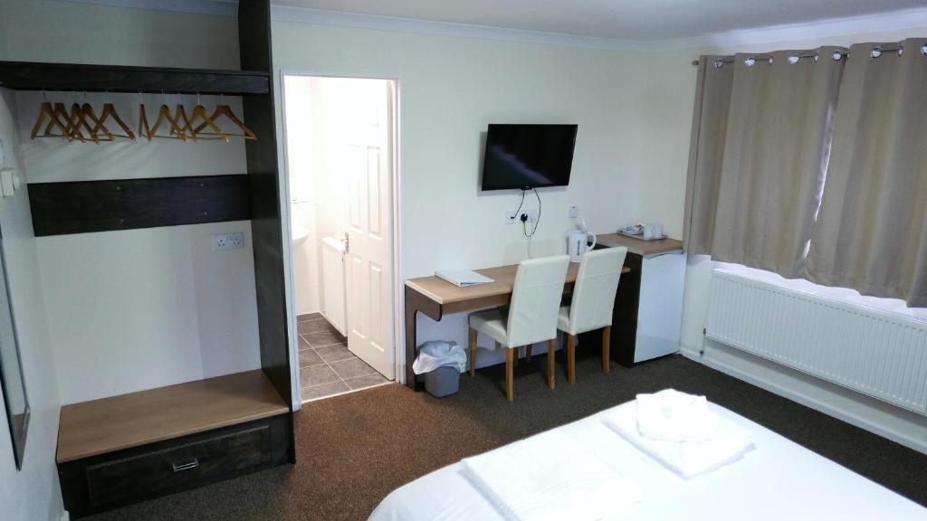 a hotel room with a desk and a bed and a room at Warrens Village Motel and Self Catering in Clevedon