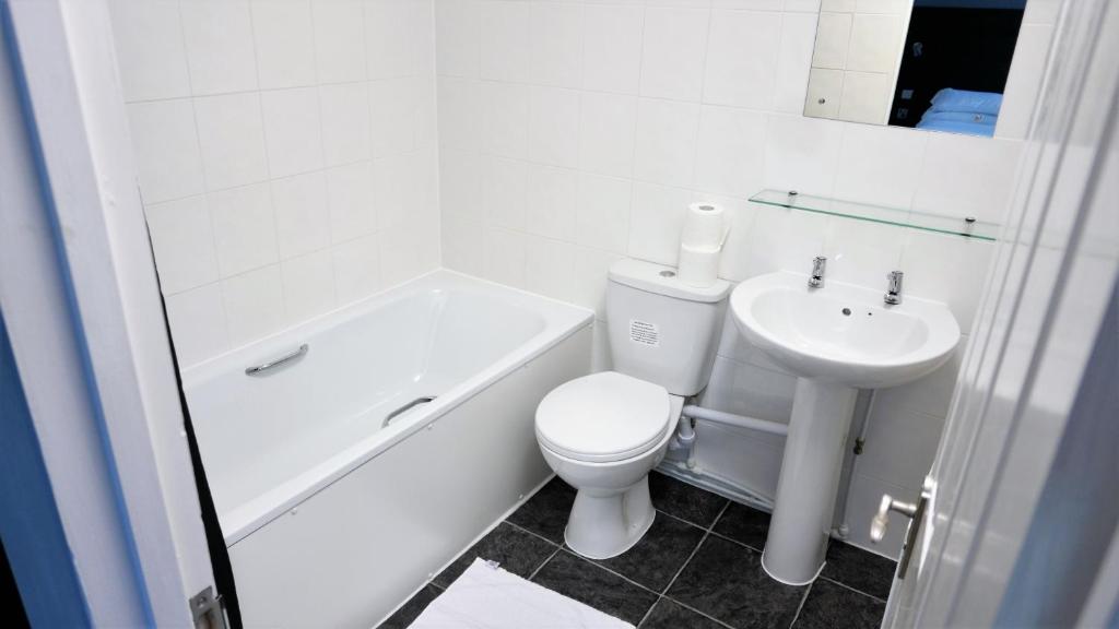 a white bathroom with a toilet and a sink at Warrens Village Motel and Self Catering in Clevedon