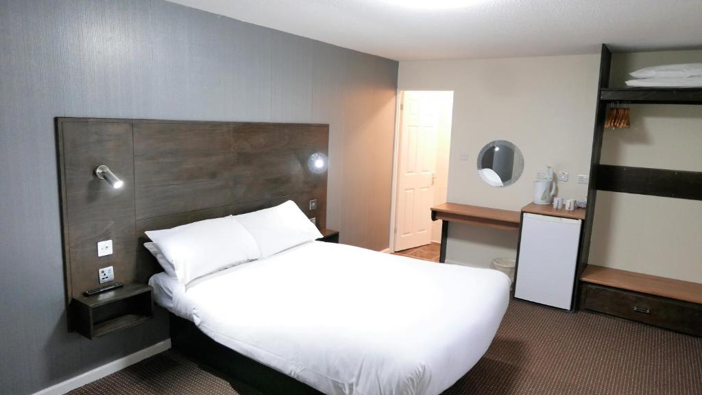 a bedroom with a white bed with a wooden headboard at Warrens Village Motel and Self Catering in Clevedon