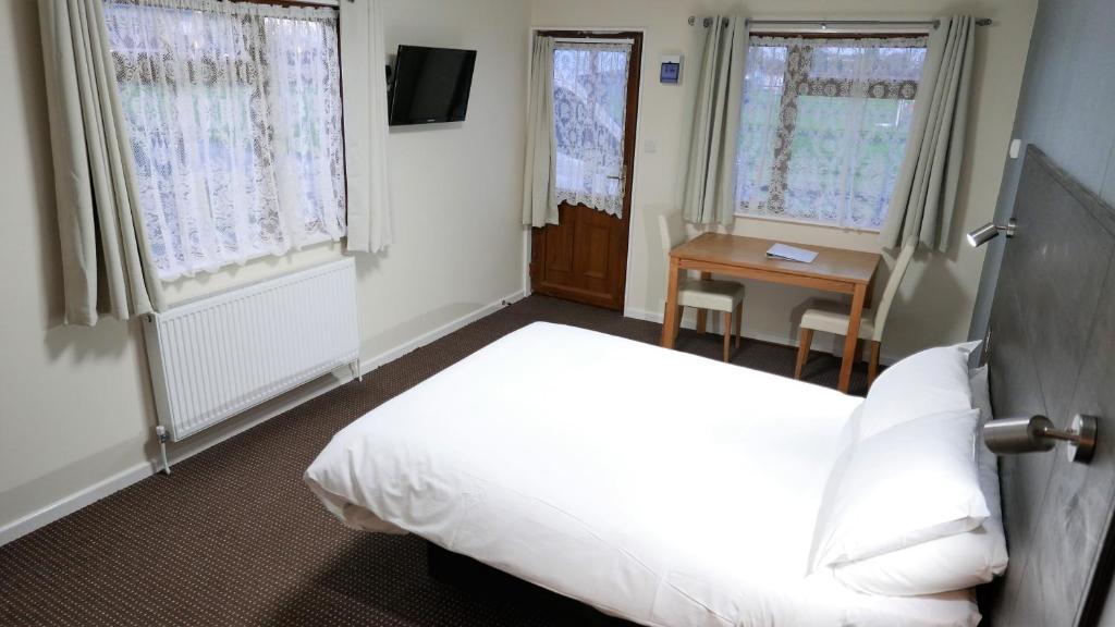 a bedroom with a bed and a table and windows at Warrens Village Motel and Self Catering in Clevedon