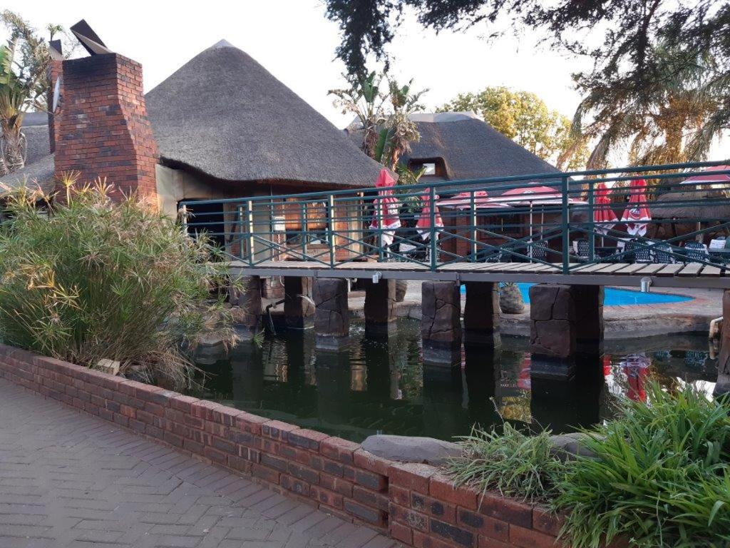 uma ponte sobre um lago num parque em Ambassador Lodge Kimberly em Kimberley