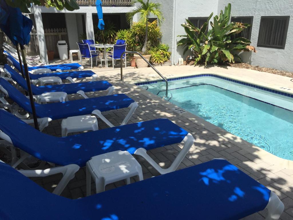 a group of blue lounge chairs next to a swimming pool at Sabal Palms Inn in St. Pete Beach