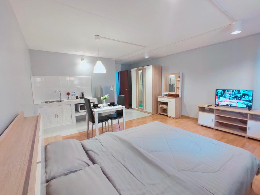 a white bedroom with a large bed and a kitchen at Popular Condo เมืองทองธานี in Pak Kret