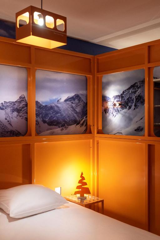 a room with a bed with four pictures on the wall at Hotel Base Camp Lodge - Bourg Saint Maurice in Bourg-Saint-Maurice