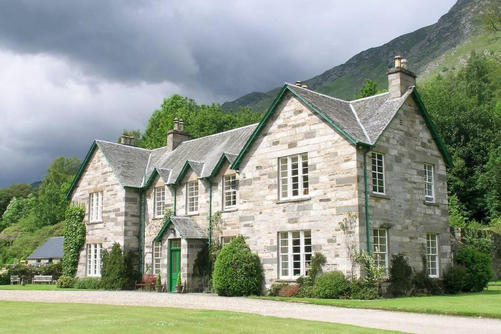 una grande casa in pietra con una porta verde di Chesthill House and Estate, Glen Lyon ad Aberfeldy