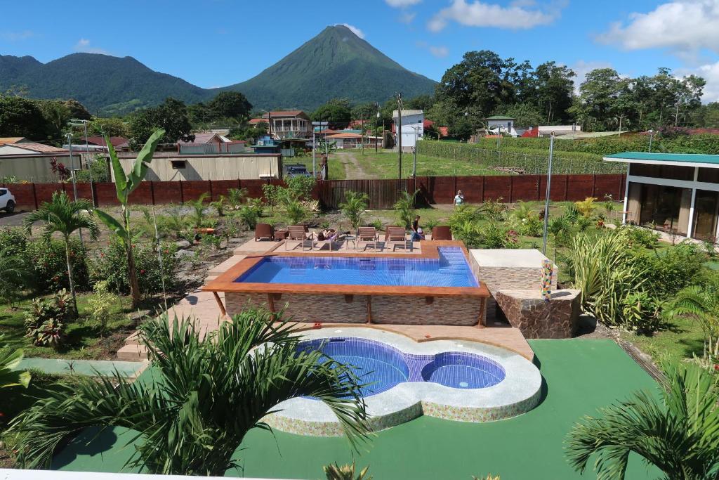 una piscina en un patio con una montaña al fondo en Hotel Secreto La Fortuna, en Fortuna