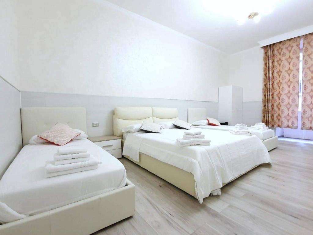 2 letti in una camera da letto con pareti bianche e pavimenti in legno di Oscar suite home a Roma