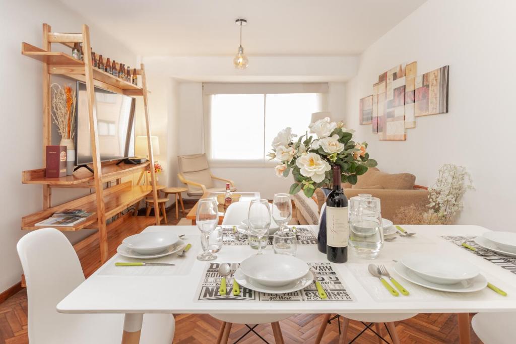 uma mesa de jantar branca com pratos brancos e flores em Tu Apart En Bariloche 2 em San Carlos de Bariloche