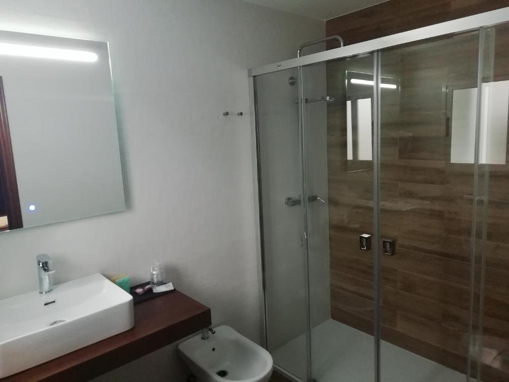 a bathroom with a glass shower and a sink at Hotel Montearoma in Valverde del Camino