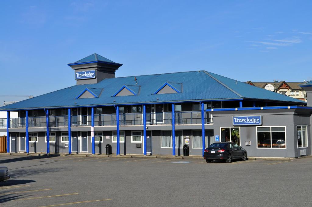 a building with a car parked in a parking lot at Travelodge by Wyndham Langley in Langley