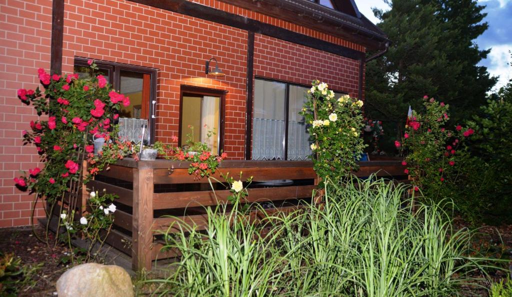 a house with flowers in front of it at Apartament Poddąbie - basen, kort tenisowy, parking in Poddąbie