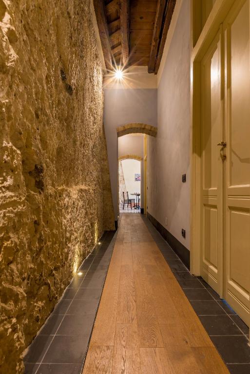 a hallway with a stone wall and a wooden floor at Cappuccine GuestHouse in Cagliari
