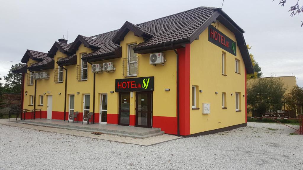 un edificio amarillo y rojo con una tienda en Hotelik SJ en Lodz