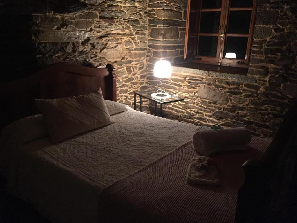 a bedroom with a bed in a stone walled room at Casa Ferreiro - Campo da Cruz - Lugo in Baltar