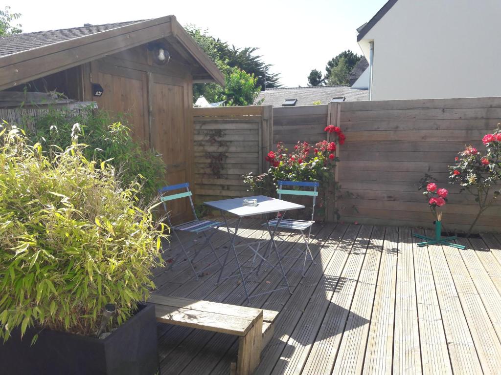 een patio met een tafel en stoelen en een hek bij La Voile Bleue in La Trinité-sur-Mer