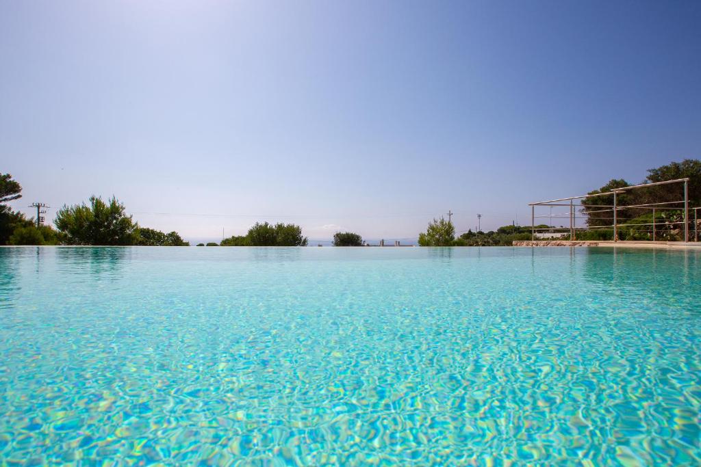a large pool of blue water with trees in the background at VILLA BIANCA con piscina e vista mare in Gagliano del Capo