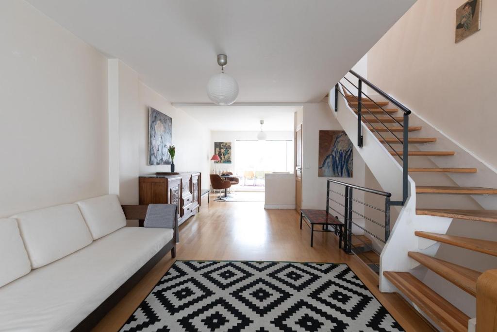 a living room with a white couch and stairs at Paris-Maison-appartement-7 chambres métro Jourdain in Paris