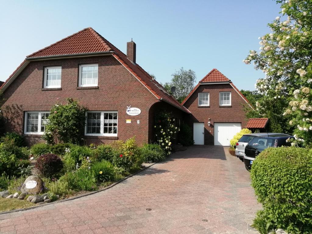 a brick house with a car parked in the driveway at Haus Mühlenblick in Neuharlingersiel