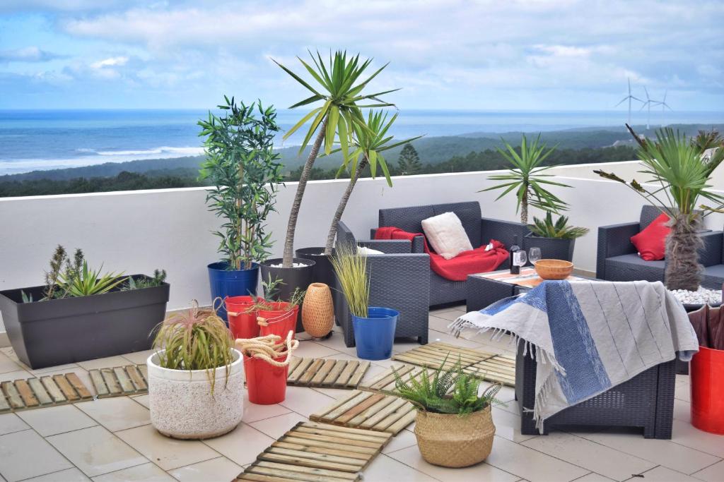 a patio with chairs and potted plants on a balcony at Nazaré Penthouse Big Terrace, ocean views in Nazaré